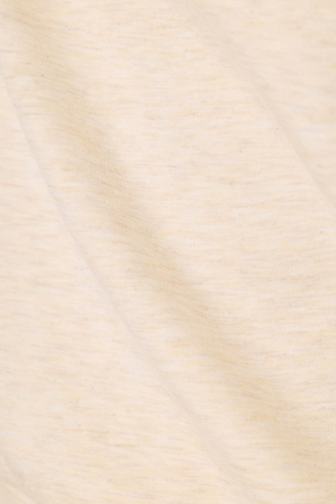 A close-up of a soft, heathered cream or off-white fabric texture with subtle warm beige undertones and gentle folds.