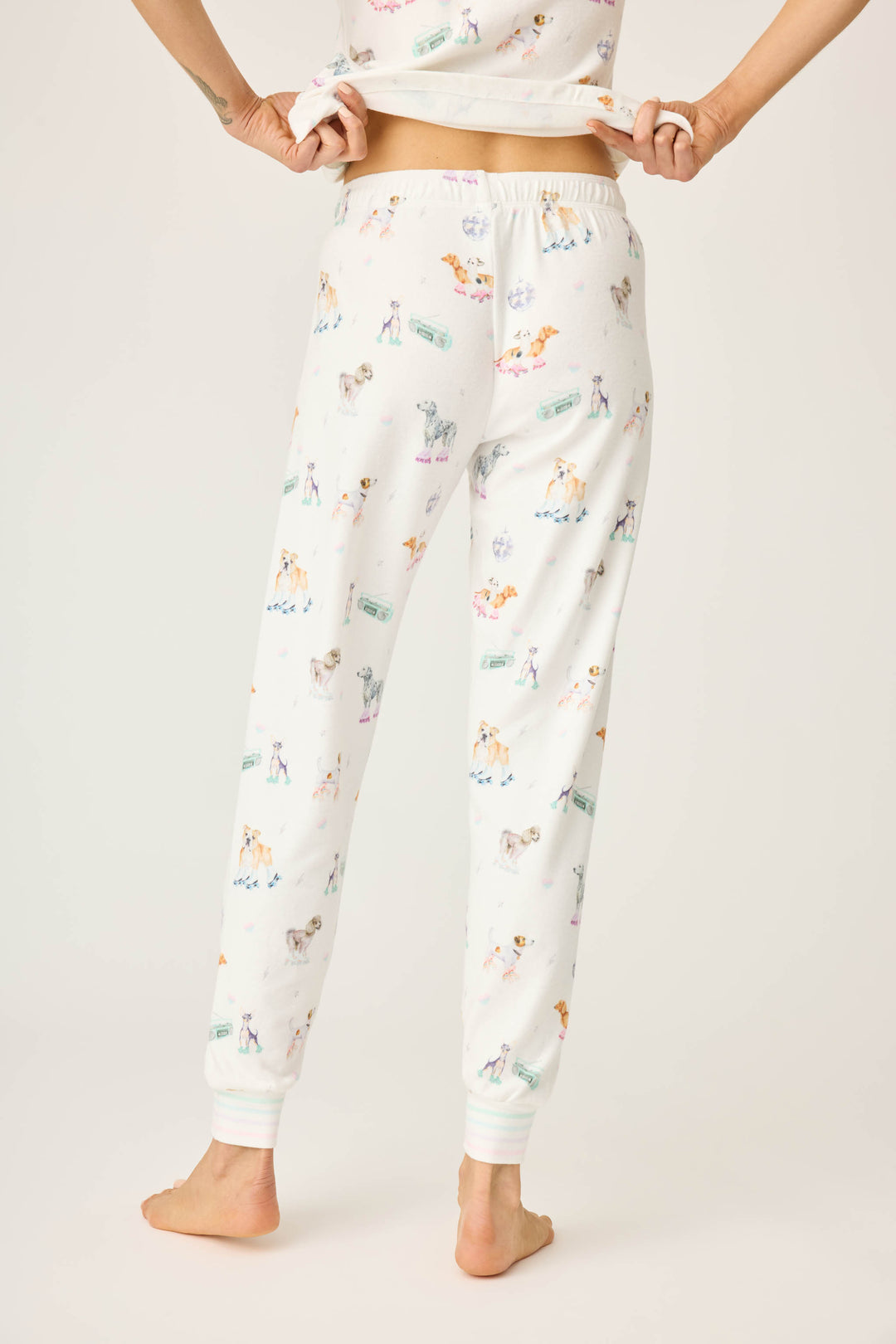 Women's ivory pajama pant with dogs on rollerskates pattern. Relaxed fit with banded bottom.