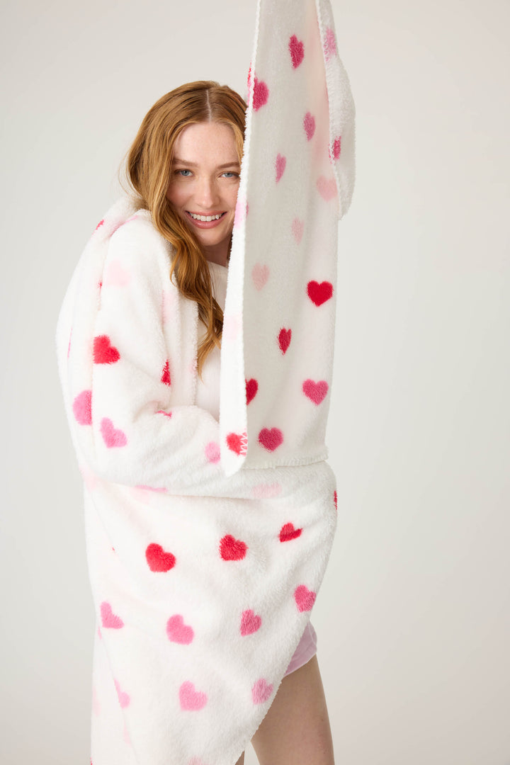 Plush ivory blanket with pink heart pattern.