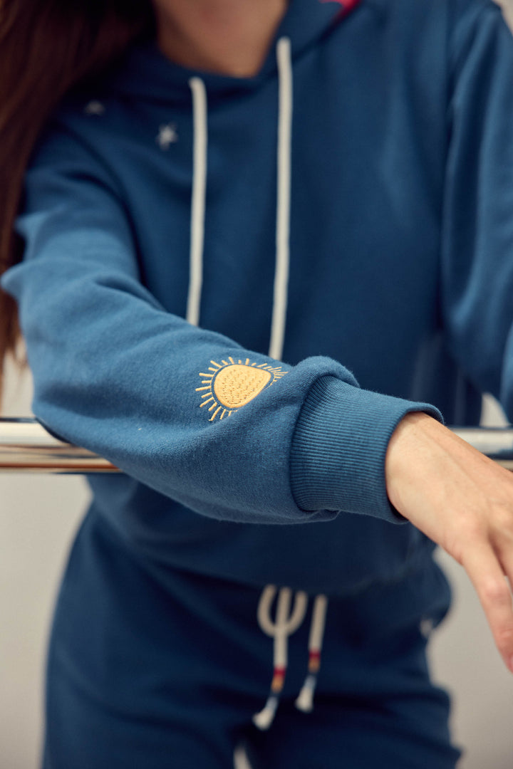 Navy pullover hoody for women in vintage fleece with nautical-inspired embroidery placements (seashell, sun, sailboat, stars)