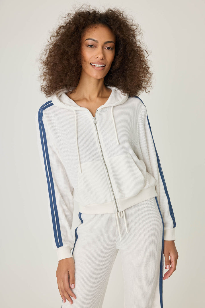 Women's ivory zip hoodie with navy athletic stripes on sleeves. Zip front with two pockets.