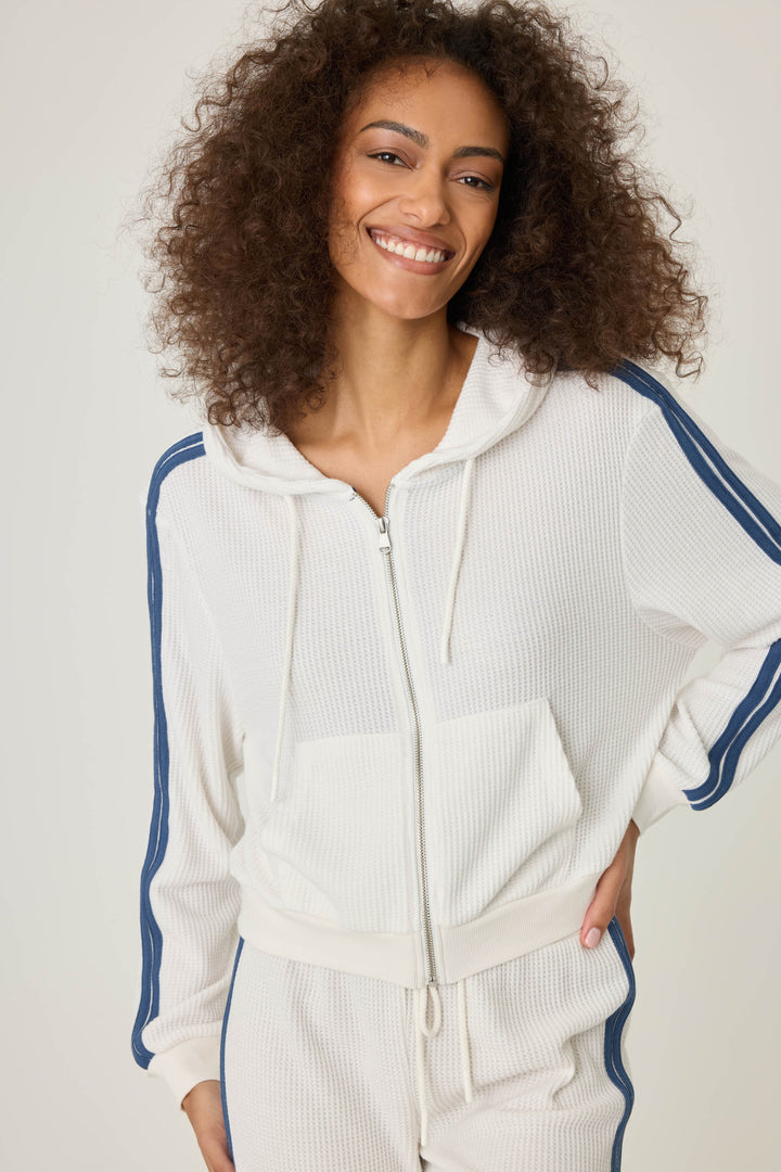 Women's ivory zip hoodie with navy athletic stripes on sleeves. Zip front with two pockets.