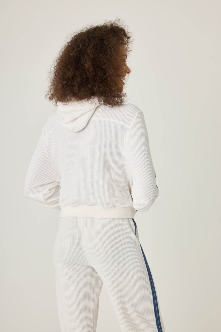 Women's ivory zip hoodie with navy athletic stripes on sleeves. Zip front with two pockets.