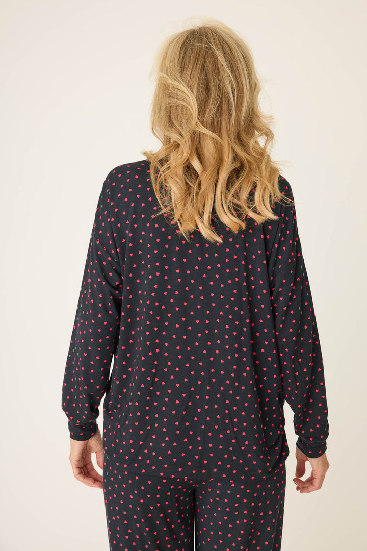 Women's black long sleeve pj top with pink heart pattern.