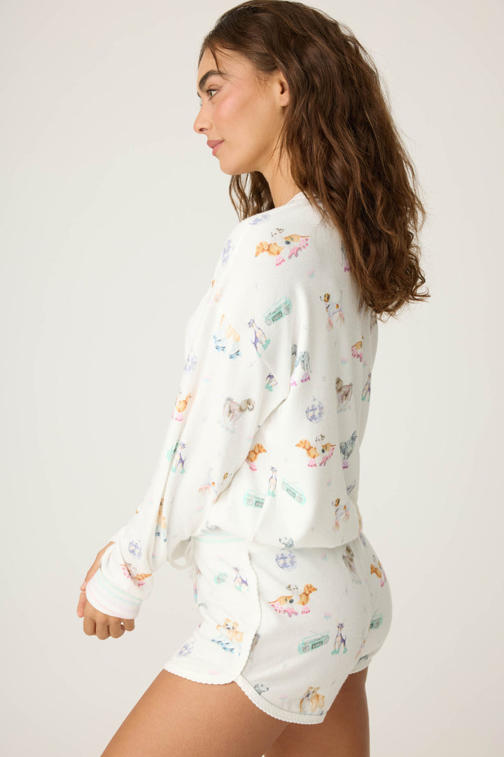 Women's ivory lounge top with dogs on rollerskates pattern. Relaxed fit with banded bottom.