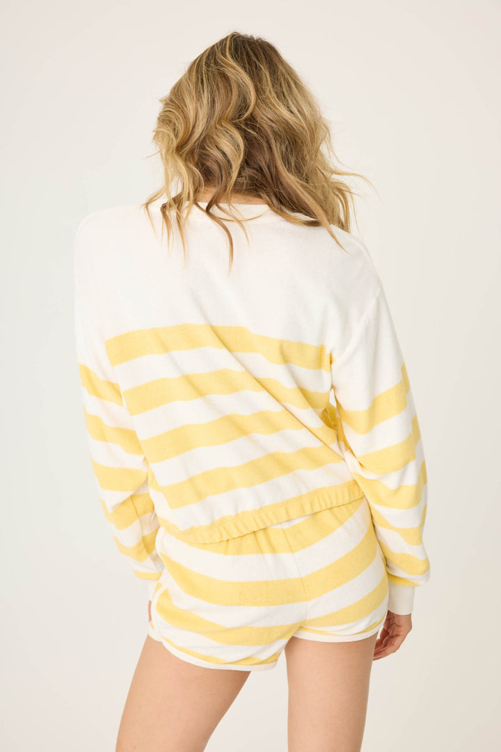 Ivory-yellow terry stripe with blue PARADISE embroidery on front. Long sleeve with elastic hem, sits at waist.