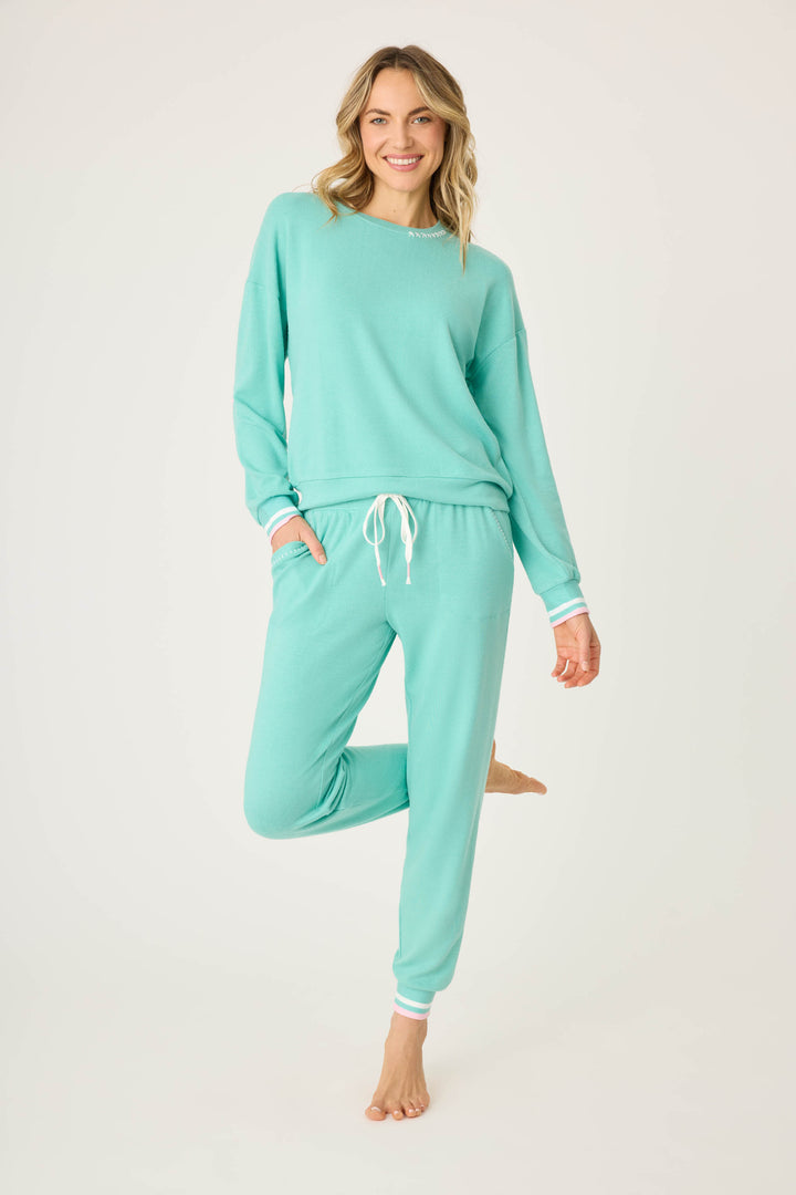 Teal green lounge set for women. Top has pink star print on elbows, pant has pockets with scallop-edging detail. Striped banded cuffs on top & pant.