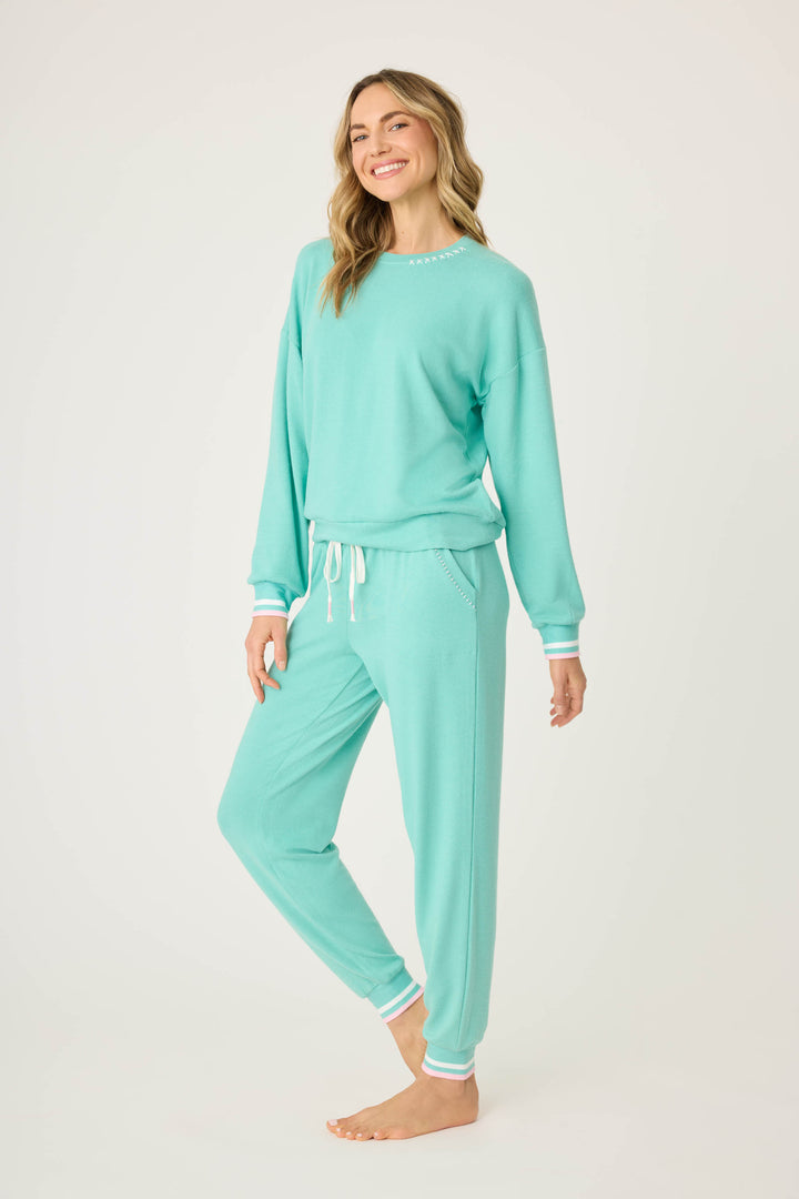 Teal green lounge set for women. Top has pink star print on elbows, pant has pockets with scallop-edging detail. Striped banded cuffs on top & pant.