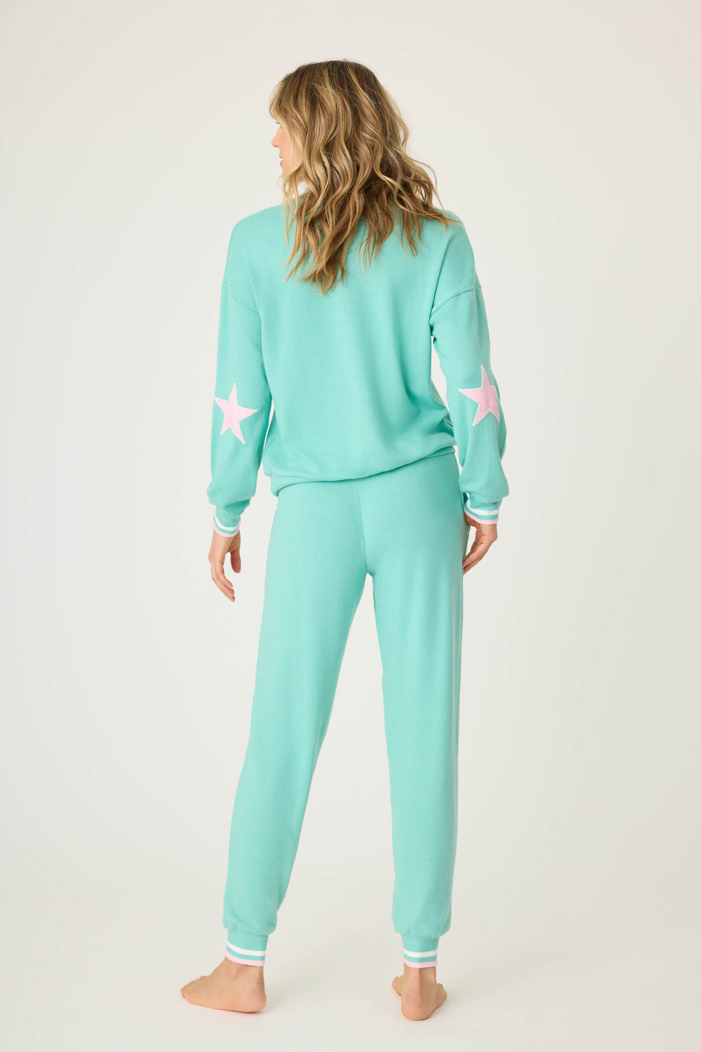 Teal green lounge set for women. Top has pink star print on elbows, pant has pockets with scallop-edging detail. Striped banded cuffs on top & pant.