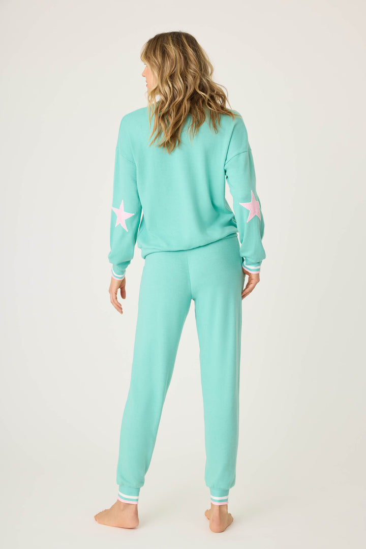Teal green lounge set for women. Top has pink star print on elbows, pant has pockets with scallop-edging detail. Striped banded cuffs on top & pant.