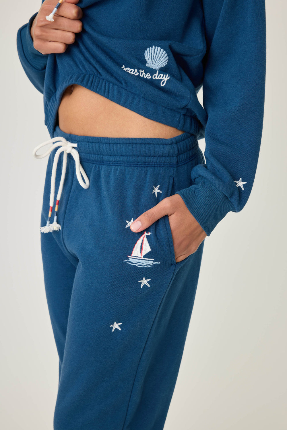 Navy jogger pant for women in vintage fleece with nautical-inspired embroidery placements (seashell, sun, sailboat, stars)