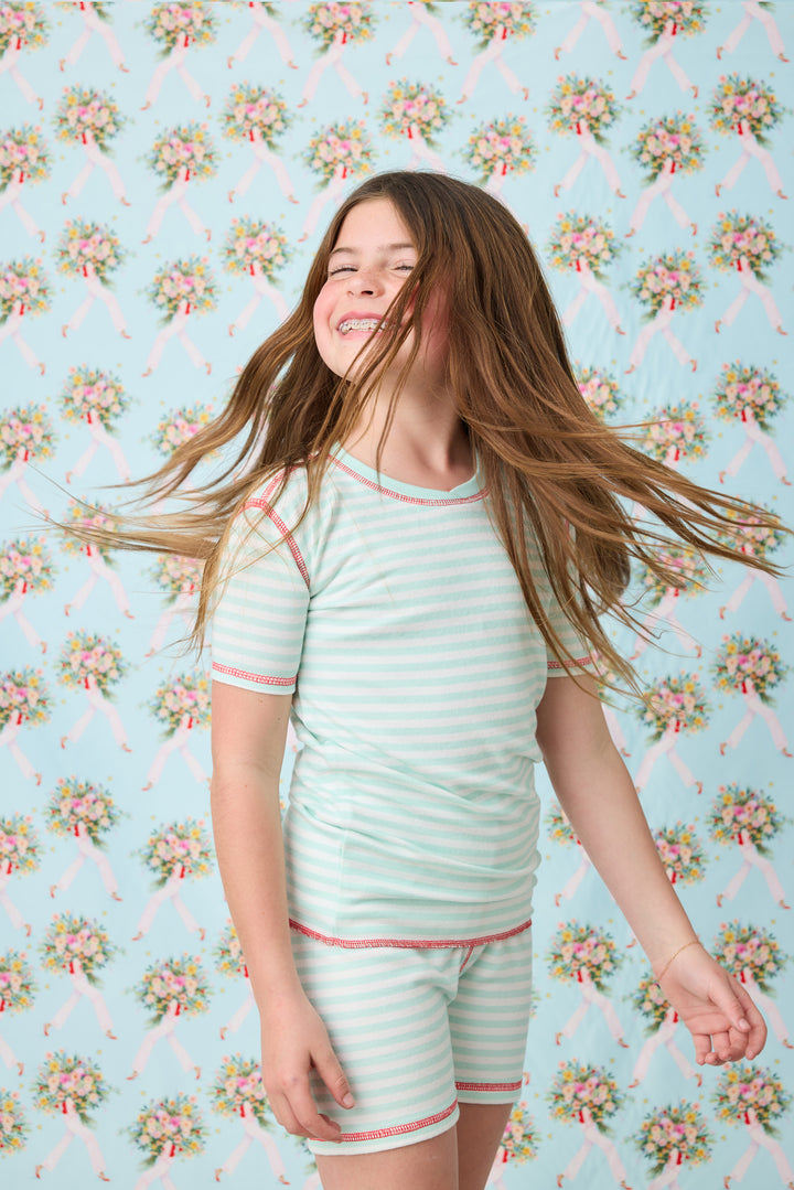 Gender-neutral kids' pajama in mint-ivory stripes with contrast red stitching.