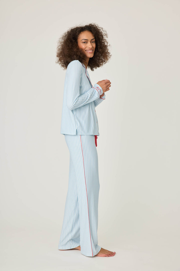 Women's classic pajama set in light blue-white striped butter jersey. Red piping at button-front top & sideseams of pant. Chest pocket with embroidered crab & matching sleep mask with 'Crabby' lettering.