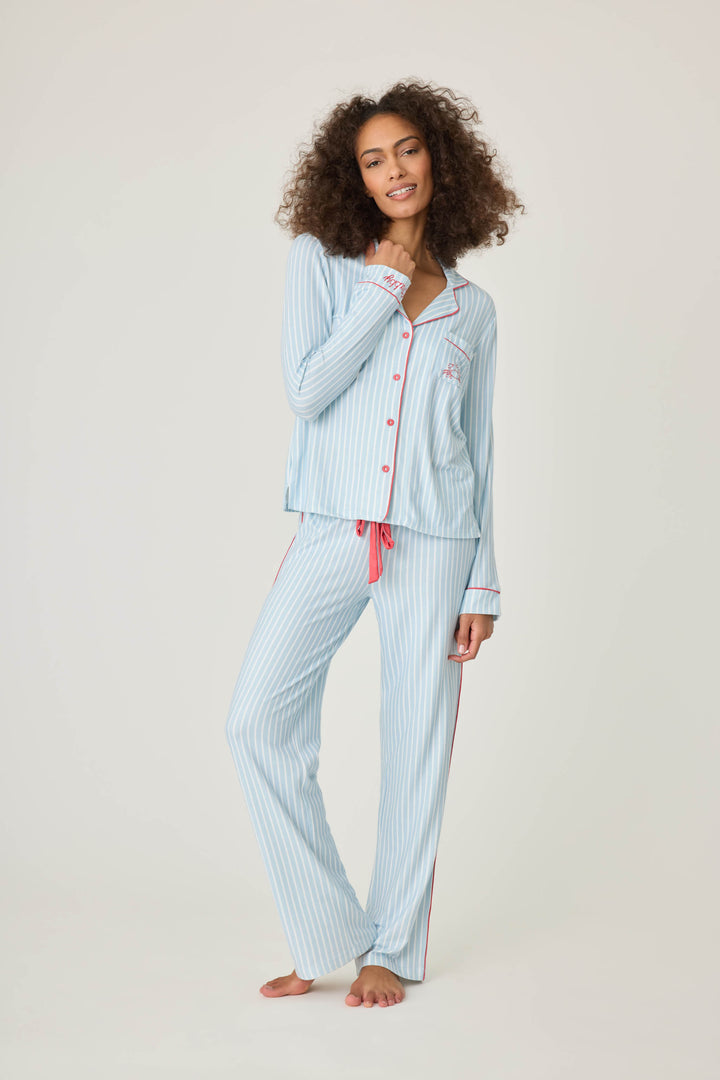 Women's classic pajama set in light blue-white striped butter jersey. Red piping at button-front top & sideseams of pant. Chest pocket with embroidered crab & matching sleep mask with 'Crabby' lettering.