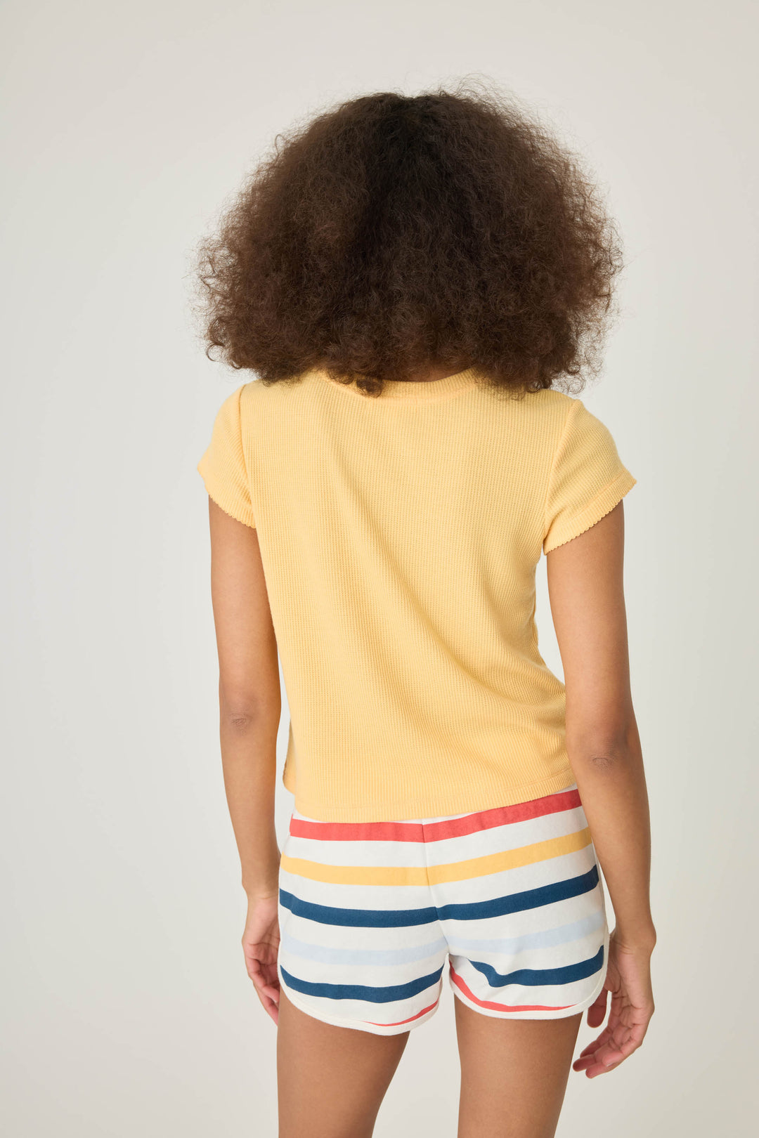 Yellow peachy waffle knit t-shirt with embroidreed shell graphic on front.