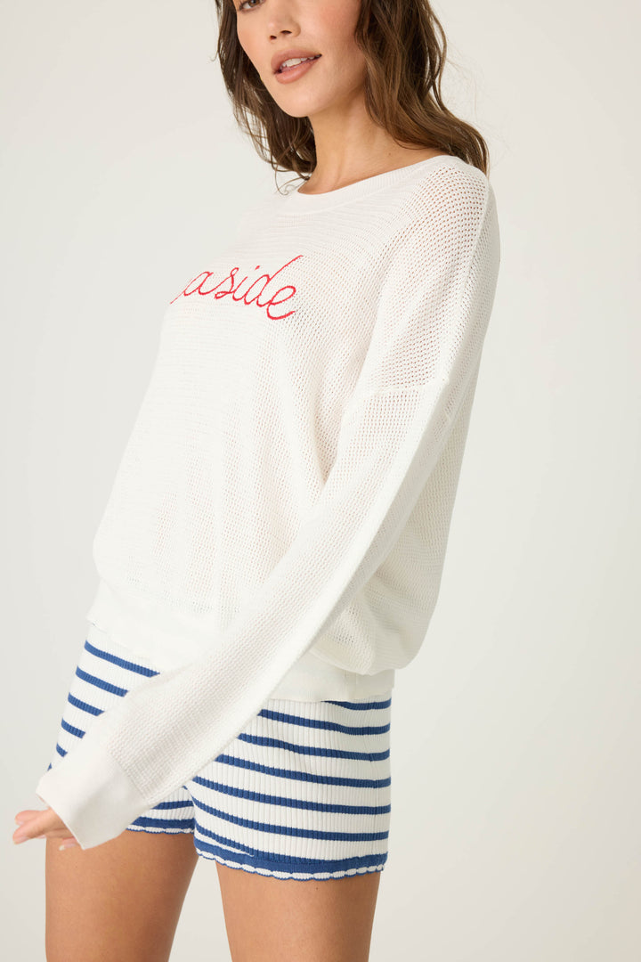 Ivory open-weave knit sweater with airy look & 'seaside' in red lettering embroidery.