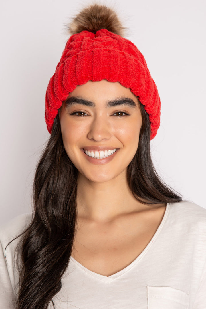 Beanie hat in red chenille knit cable pattern. Tan faux fur pom-pom on top. (7257677955172)
