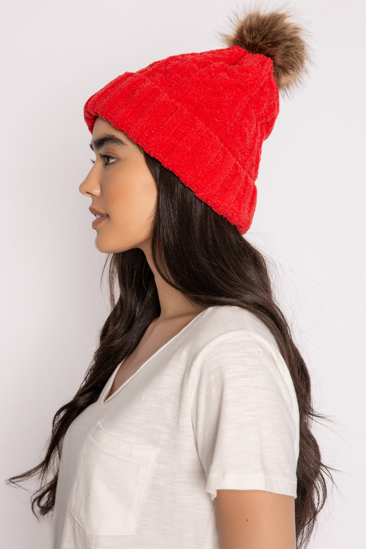 Beanie hat in red chenille knit cable pattern. Tan faux fur pom-pom on top. (7257677955172)