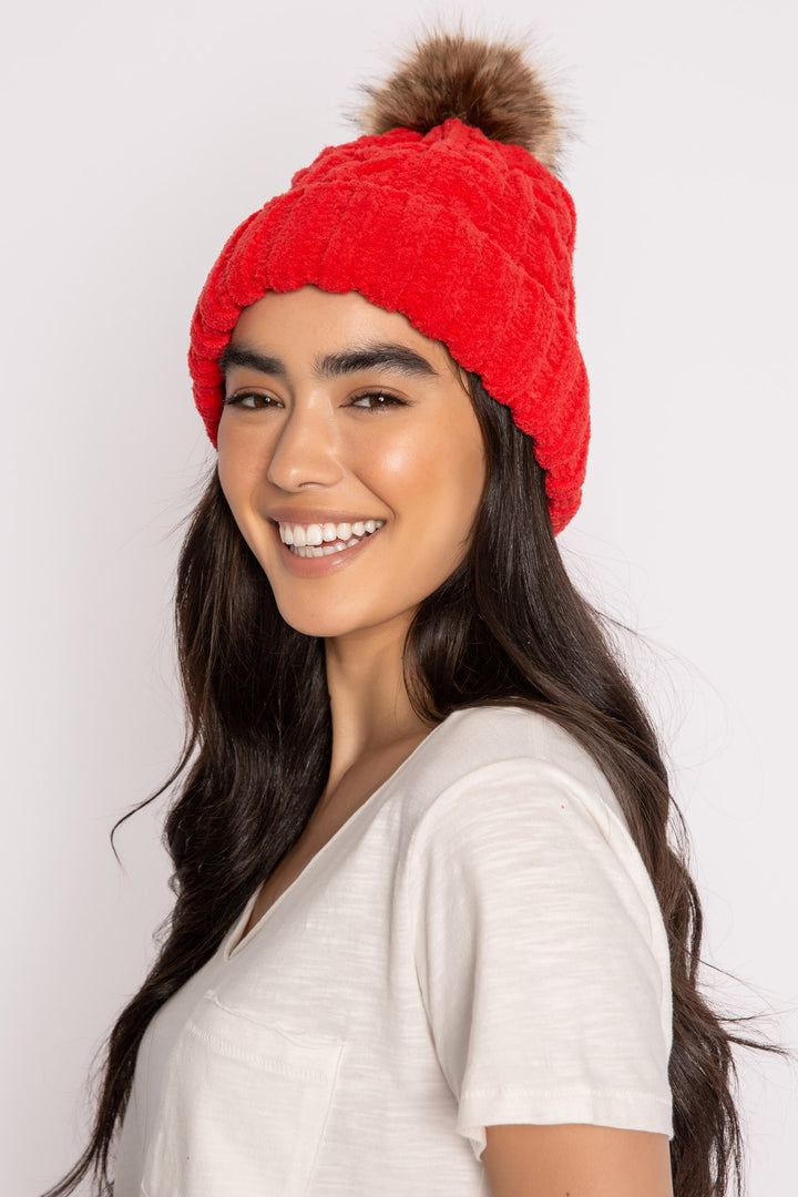 Beanie hat in red chenille knit cable pattern. Tan faux fur pom-pom on top. (7257677955172)