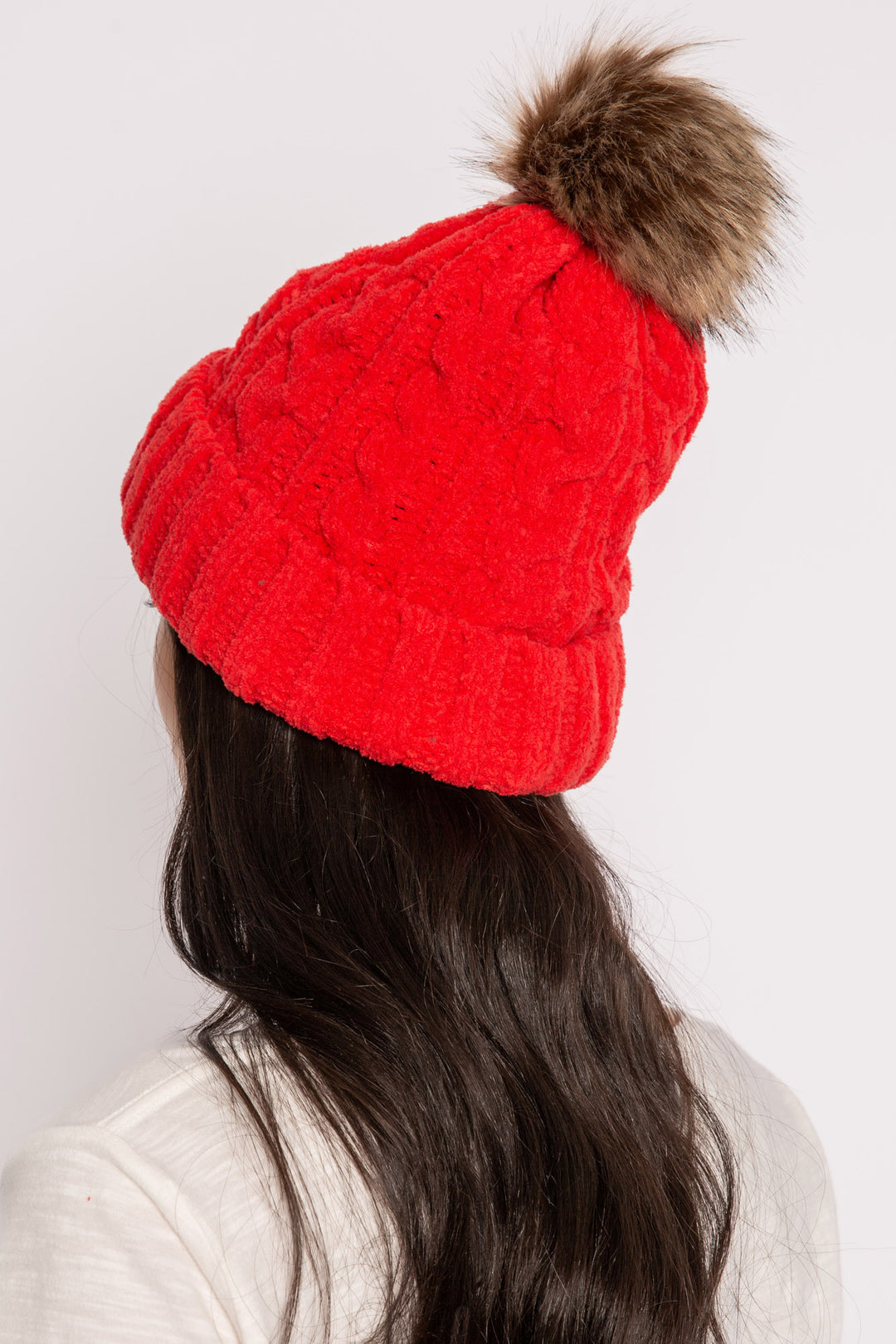Beanie hat in red chenille knit cable pattern. Tan faux fur pom-pom on top. (7257677955172)