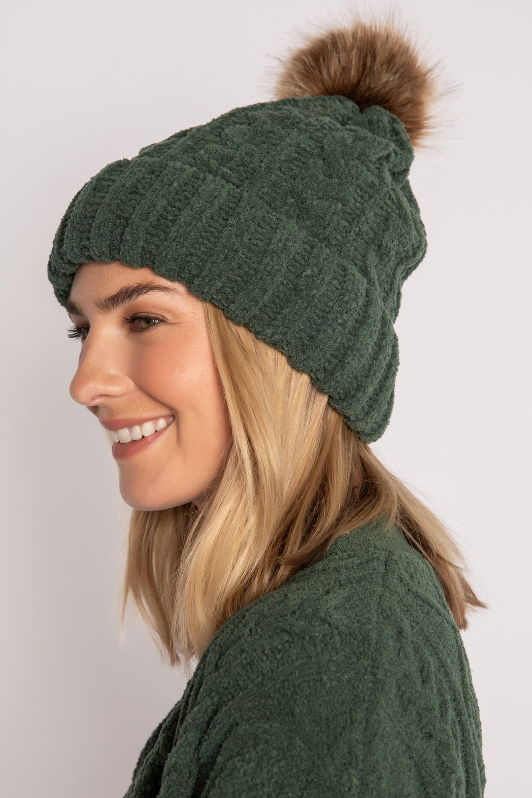 Beanie hat in dark green chenille knit with cable pattern. Tan pom-pom puff at top. (7257679265892)