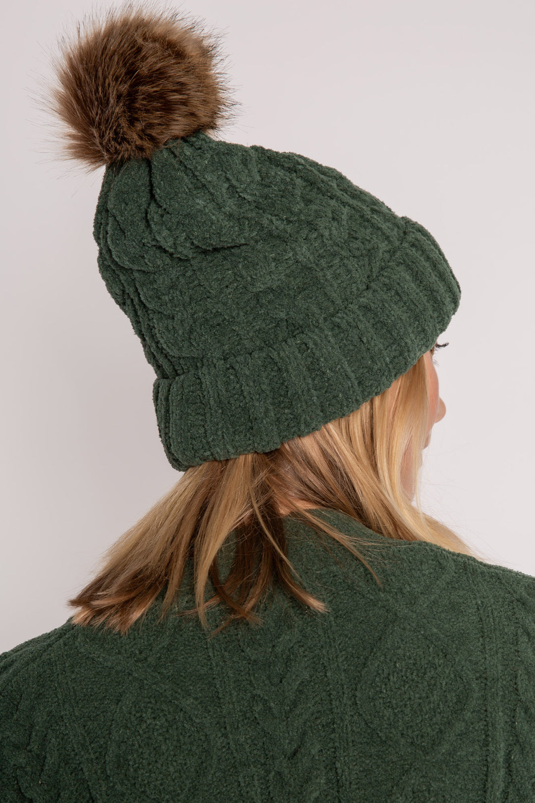 Beanie hat in dark green chenille knit with cable pattern. Tan pom-pom puff at top. (7257679265892)
